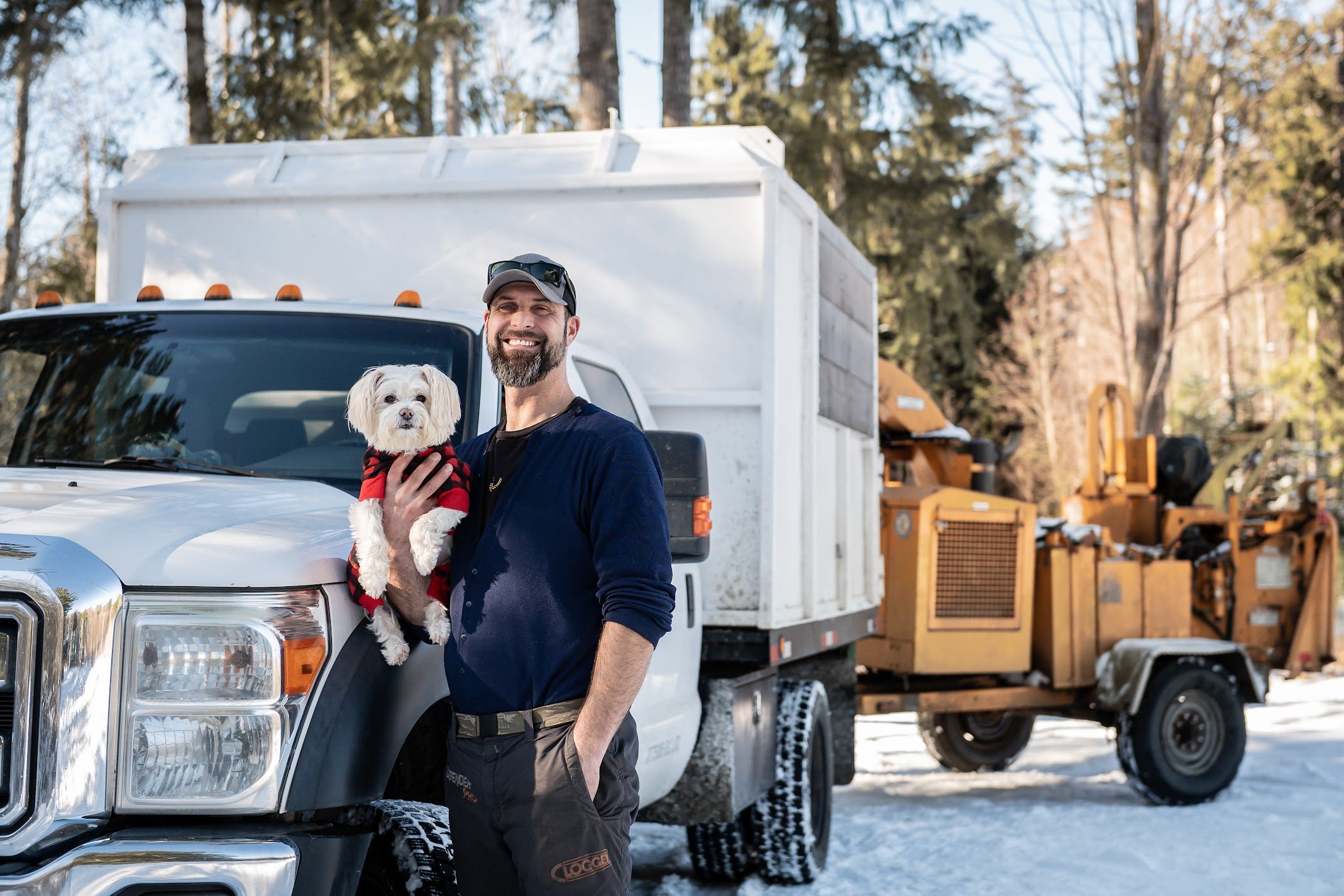 Ian Elshaw with his dog in front of the Elshaw Contracting chip truck and wood chipper